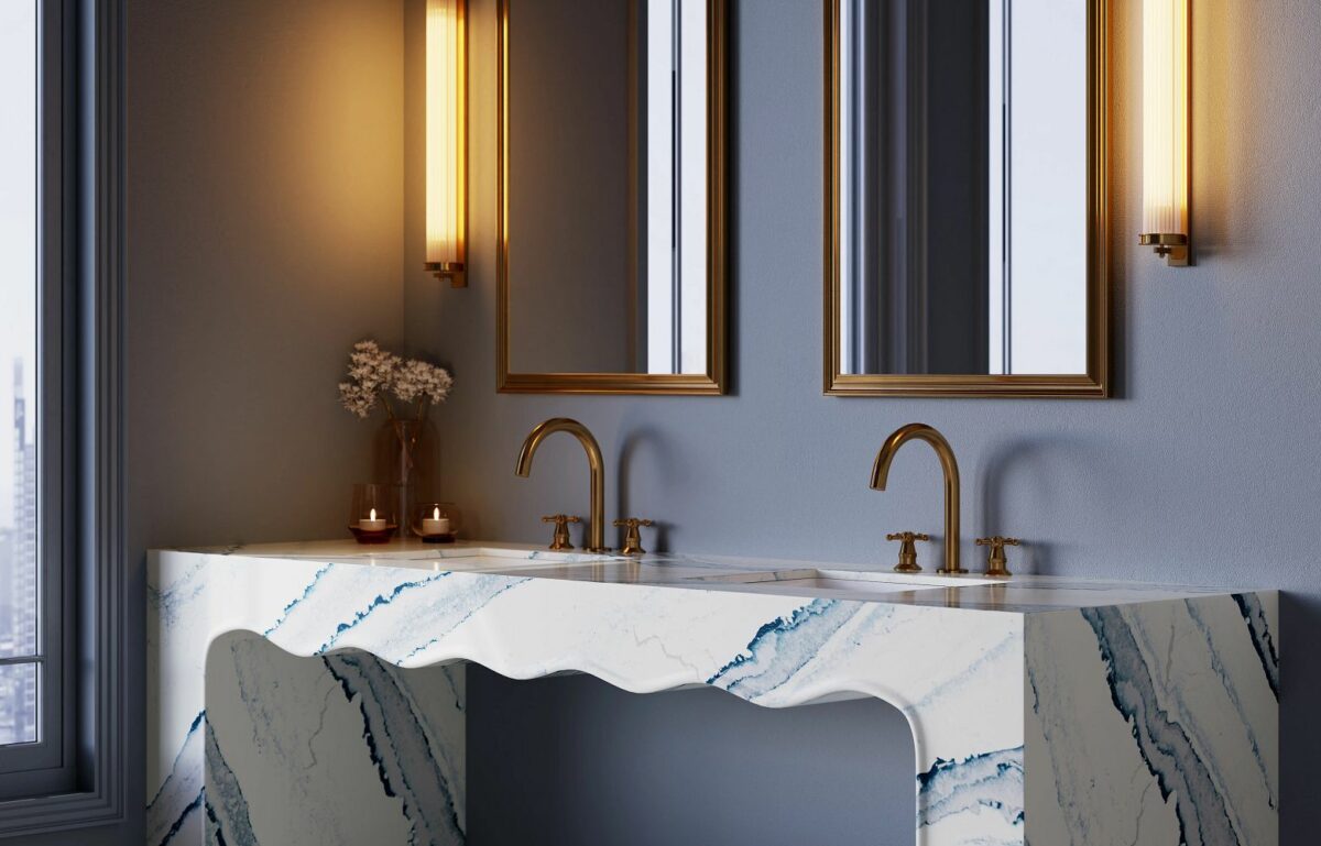 Close-up view of installed bathroom countertops using Cambria Inverness Bristol Bay Quartz countertop featuring stormy-blue waves, cool white backdrop, and debossed Inverness veins, showcasing its high gloss finish and durability for residential and commercial applications.