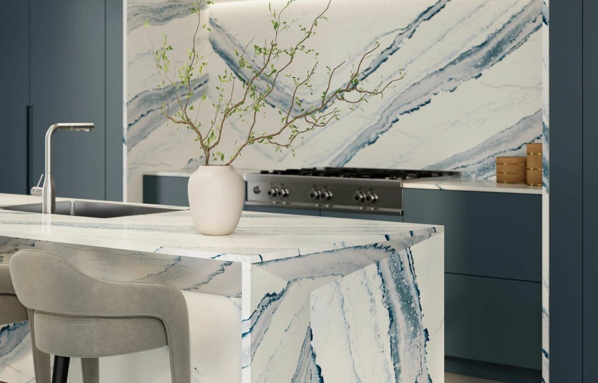 Close-up view of installed kitchen countertops using Cambria Inverness Bristol Bay Quartz countertop featuring stormy-blue waves, cool white backdrop, and debossed Inverness veins, showcasing its high gloss finish and durability for residential and commercial applications.